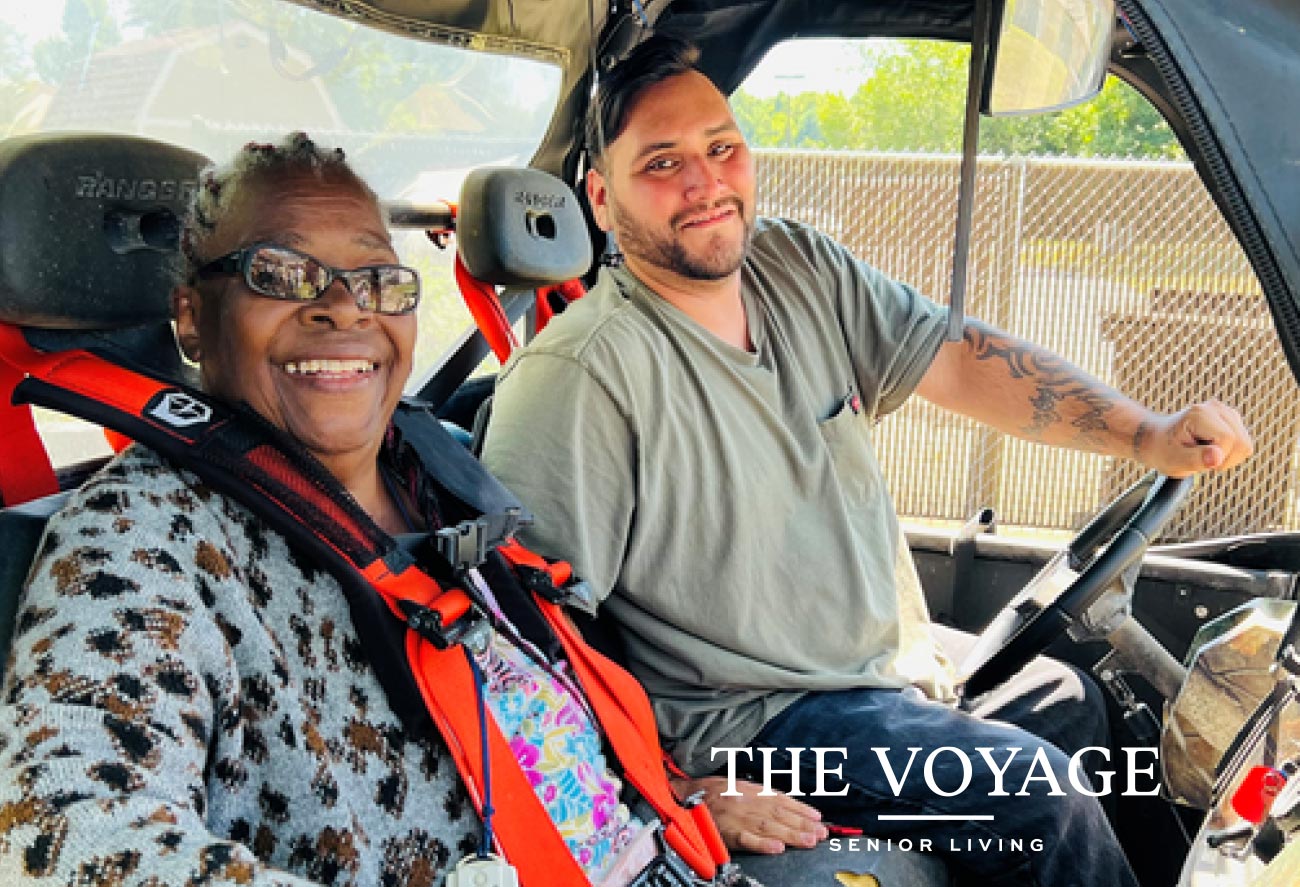 Resident riding in a go kart with Voyage Senior Living employee